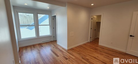 A room with wooden floors and white walls, with a window showing a pool outside.