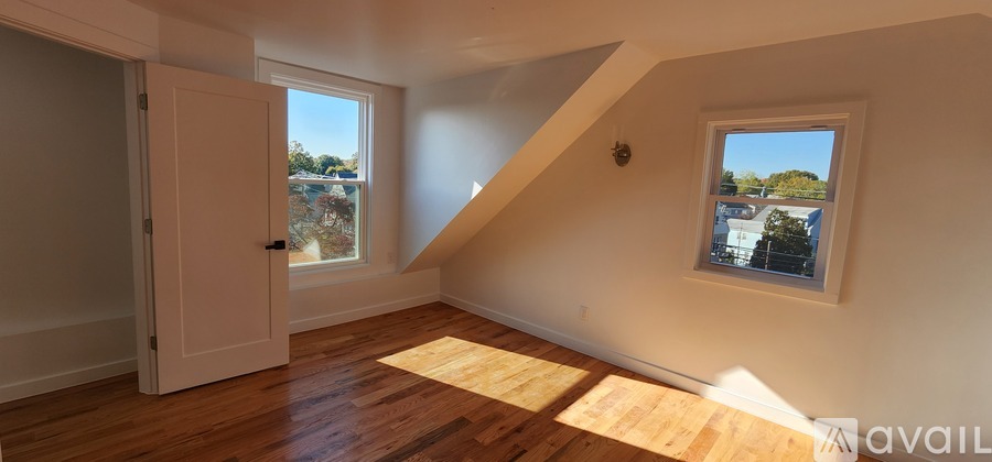A room with a wooden floor and a window with a view of a building.