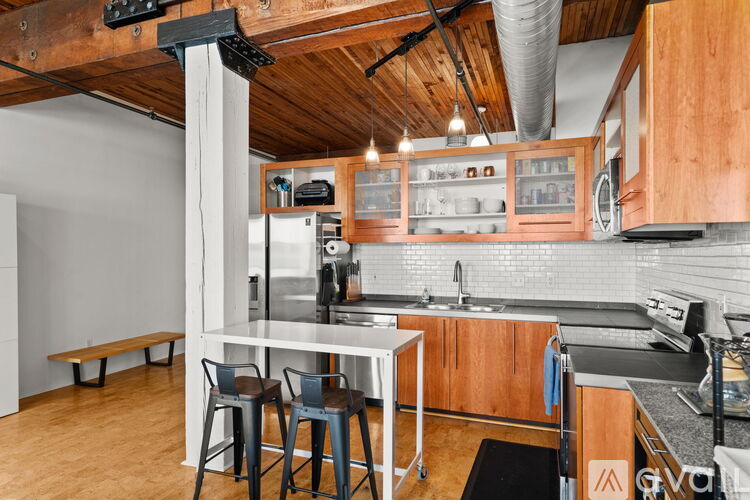 A kitchen with wooden cabinets and a white island with two chairs.