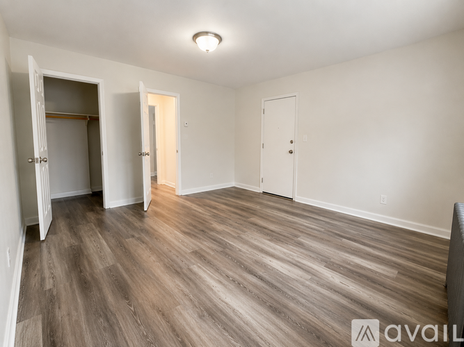 A spacious room with wooden flooring and three doors.