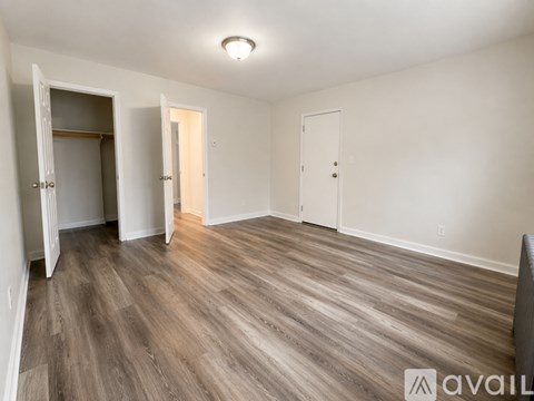 A spacious room with wooden flooring and three doors.