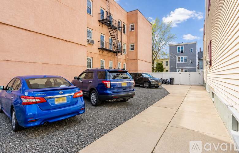 Two cars parked in front of a building with a blue car in the foreground and a purple car in the background.