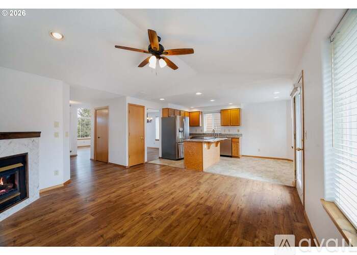 A spacious living room with a fireplace and a ceiling fan.