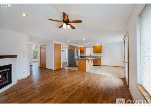 A spacious living room with a fireplace and a ceiling fan.