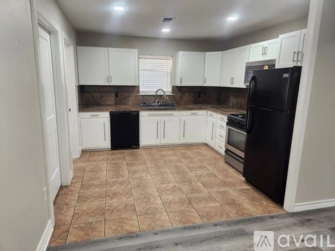 A kitchen with white cabinets and brown tiles.