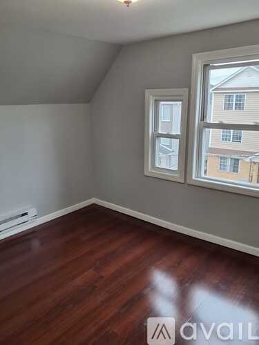 A room with wooden floors and a window overlooking a building.