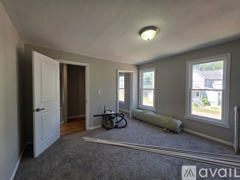 A room with a bicycle and a carpet roll on the floor.