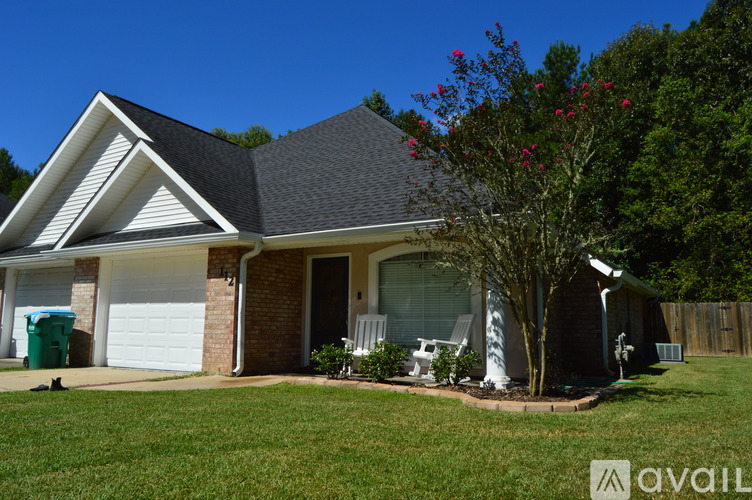 A house with a white garage door and a tree with red flowers in front.
