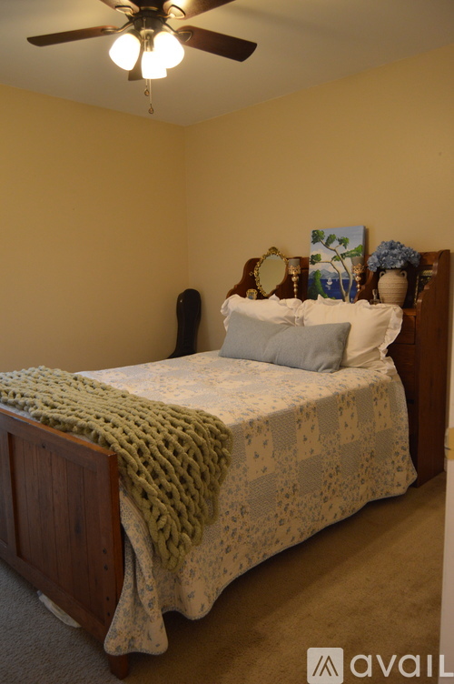 A bedroom with a bed covered in a green blanket.