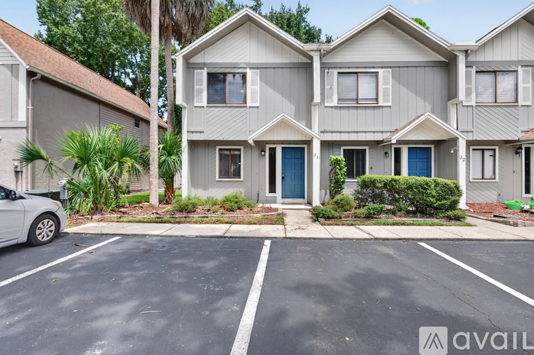 A grey house with a blue door is available for rent.