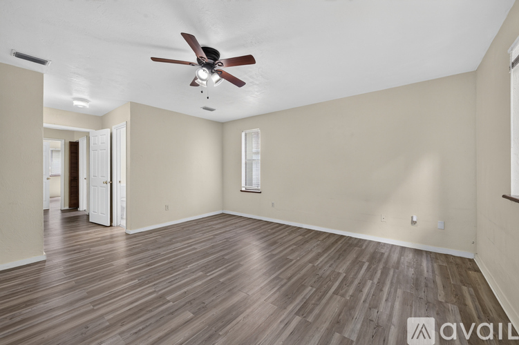 A spacious room with a ceiling fan and wooden flooring.