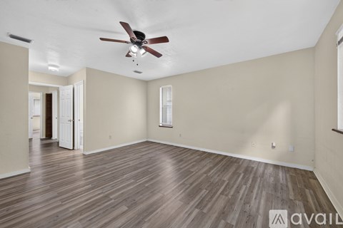 A spacious room with a ceiling fan and wooden flooring.