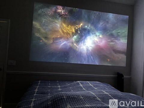 A bedroom with a large screen displaying a vibrant image of a galaxy.