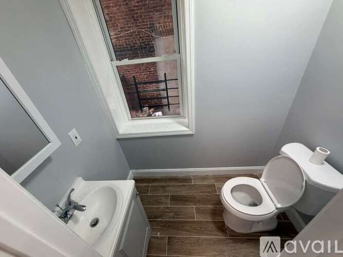 A bathroom with a toilet, sink, and window.