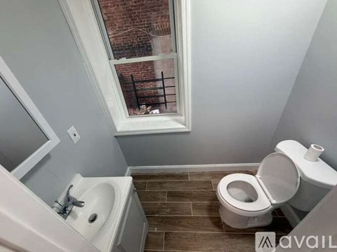 A bathroom with a toilet, sink, and window.