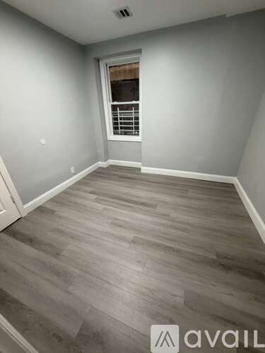 A room with wooden flooring and a window with blinds.