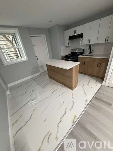 A kitchen with a white marble floor and wooden island.