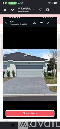 A screenshot of a mobile phone showing a photo of a house with a closed garage door.