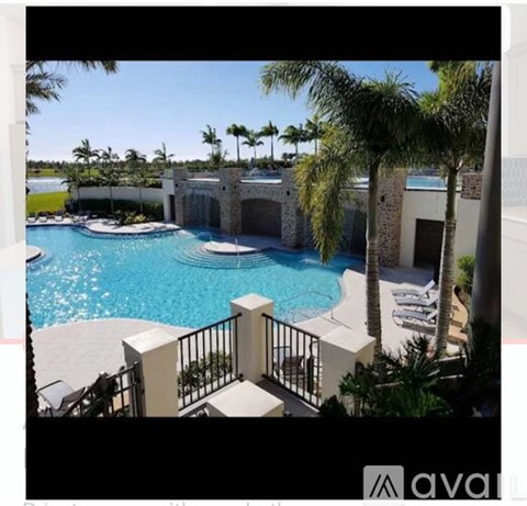 A pool surrounded by palm trees and a black fence.