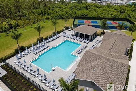 A large swimming pool surrounded by sun loungers and trees.