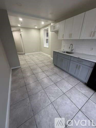 A kitchen with white cabinets and a tiled floor.