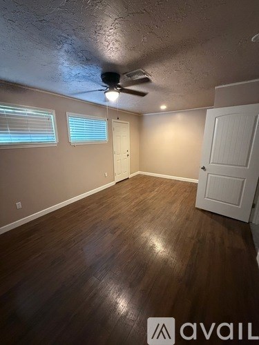 A room with a ceiling fan and wooden flooring.