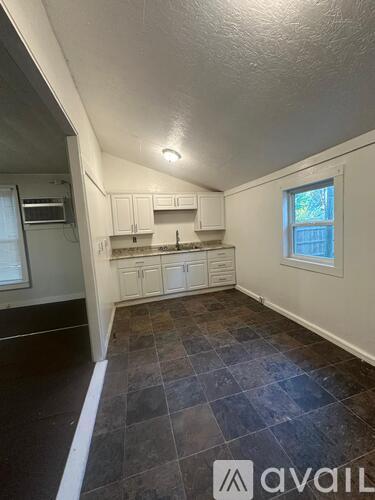 A kitchen with white cabinets and a window.