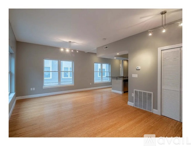 A spacious room with wooden floors and a large window.