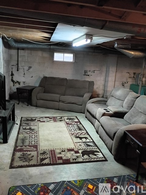 A living room with a rug on the floor and a couch and a chair.