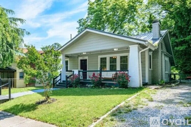A small white house with a front porch and a green lawn.