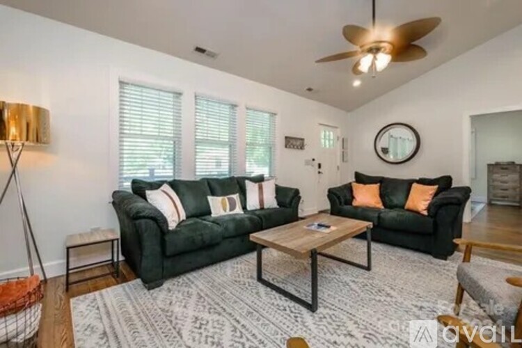 A living room with a green couch, a coffee table, and a ceiling fan.