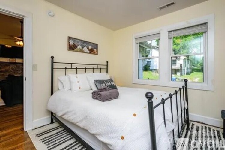 A bedroom with a black metal bed frame and white bedding.