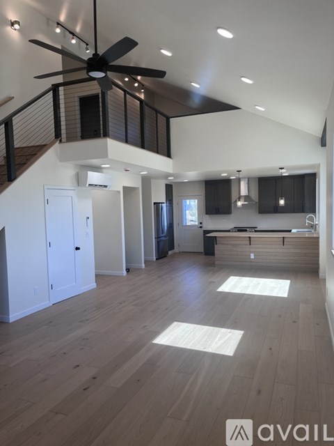 A spacious open floor plan with a ceiling fan and hardwood floors.