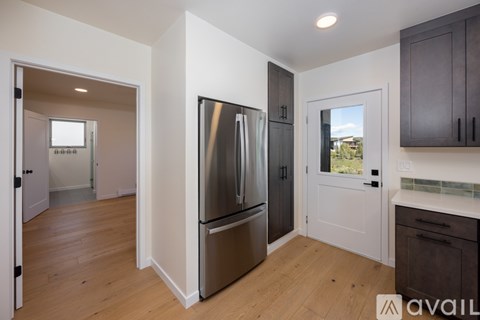 A kitchen with a refrigerator, cabinets, and a window.