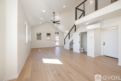 A spacious room with wooden floors and a ceiling fan.