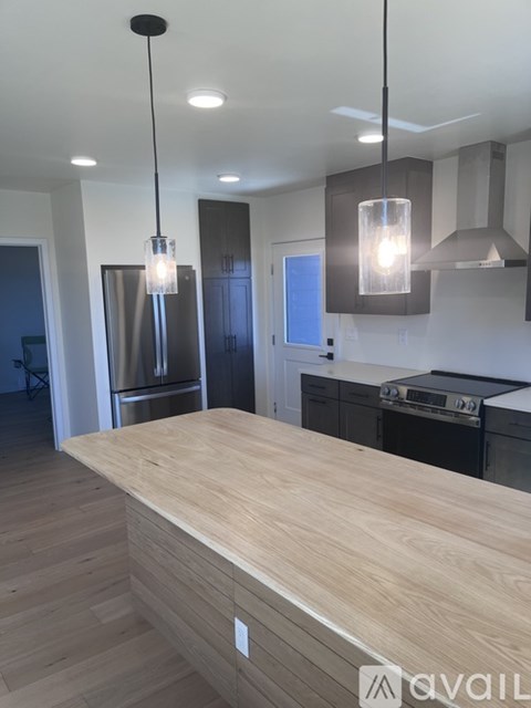 A modern kitchen with a wooden countertop and pendant lights.