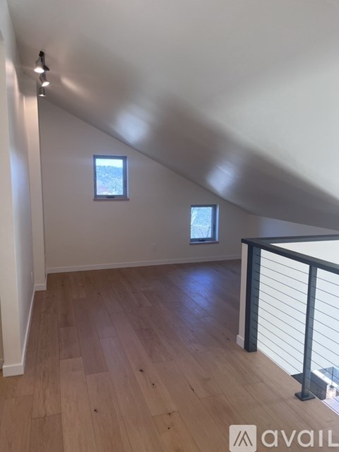 A room with wooden flooring and a window with a view of trees.