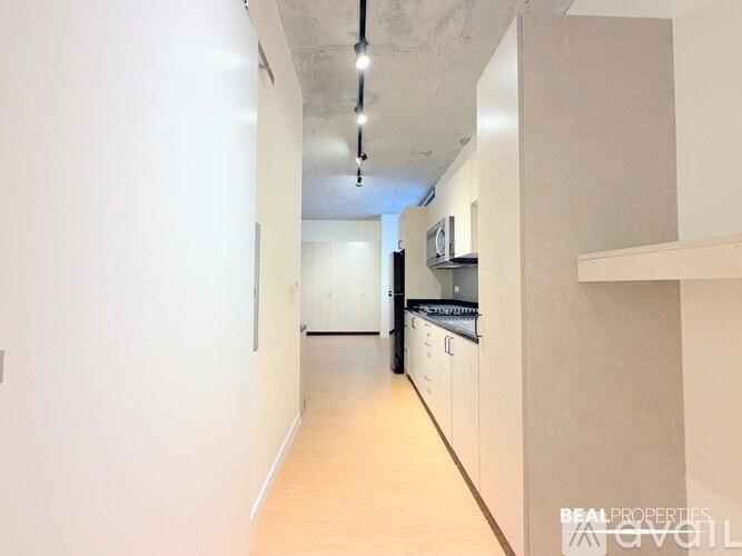 A long, narrow hallway with a kitchen area at the end.
