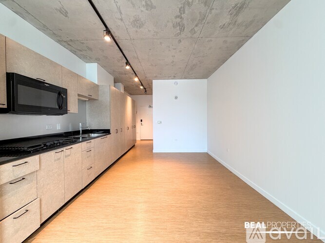 A kitchen with wooden floors and a black microwave.