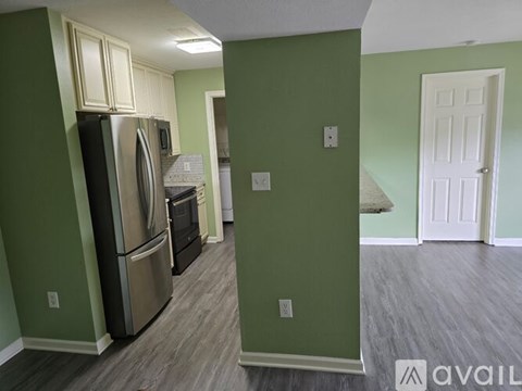 A kitchen with green walls and a stainless steel refrigerator.