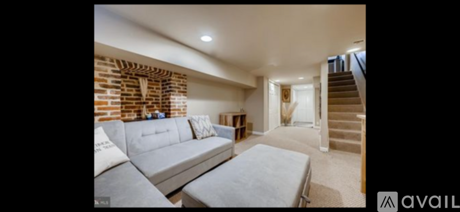 A living room with a grey sofa and a staircase.