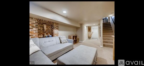 A living room with a grey sofa and a staircase.