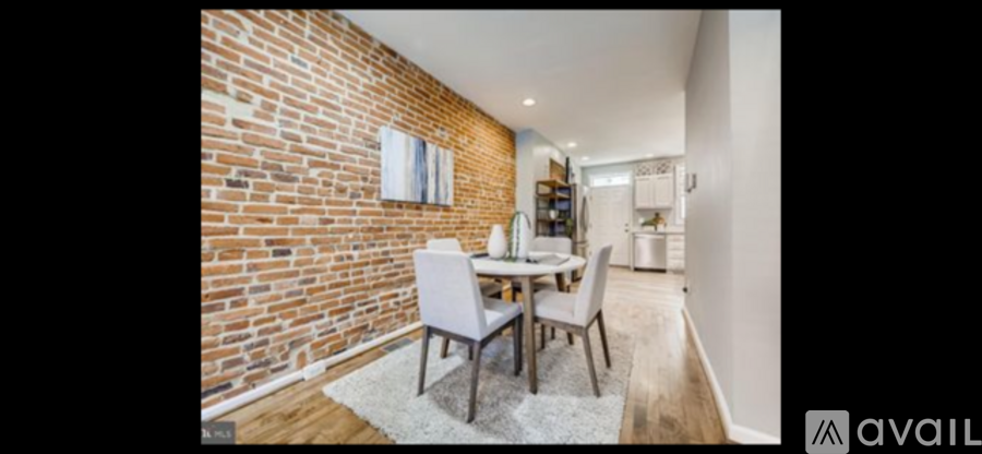 A dining area with a brick wall and a white dining table with chairs.