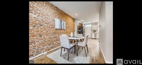 A dining area with a brick wall and a white dining table with chairs.