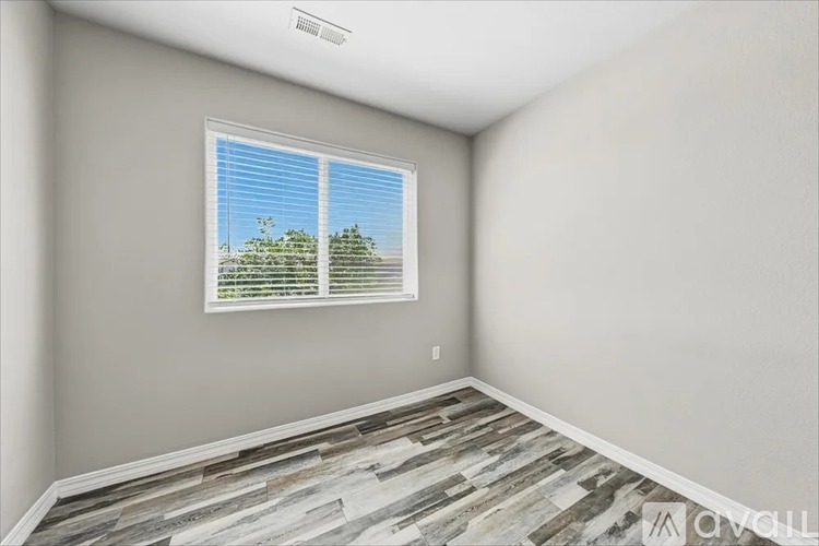 A room with a window showing a view of trees and a wall with a logo.