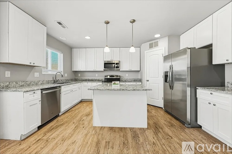 A kitchen with white cabinets and a wooden floor.