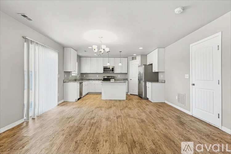 A spacious kitchen with white cabinets and a wooden floor.