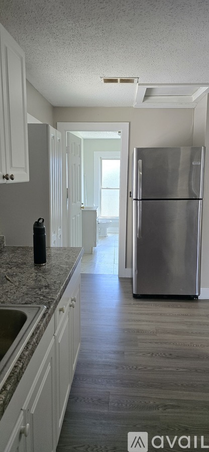 A kitchen with a refrigerator, sink, and cabinets.