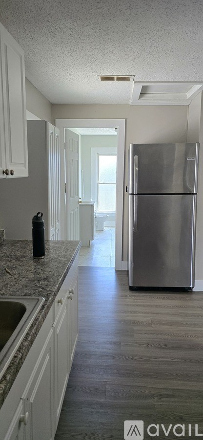 A kitchen with a refrigerator, sink, and cabinets.