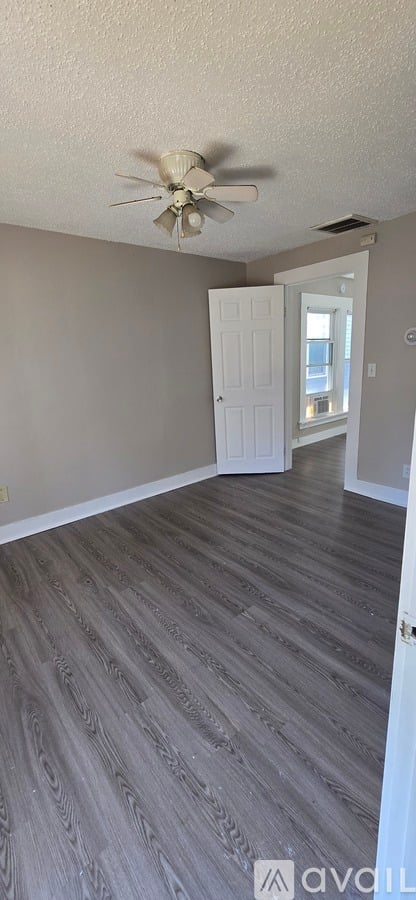 A room with a ceiling fan and a door leading to a hallway.